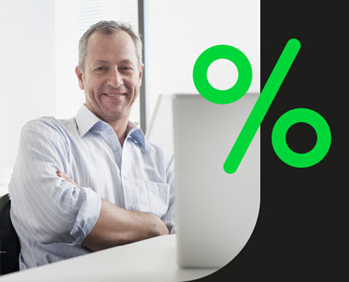 Bild eines Mannes, der entspannt lächelnd am Laptop sitzt und in die Kamera schaut – daneben eine Grafik in Form eines leuchtend grünen Prozentzeichen auf schwarzer Fläche